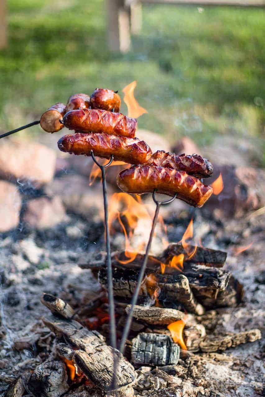 Polish sausages cooked on sticks over a campfire.