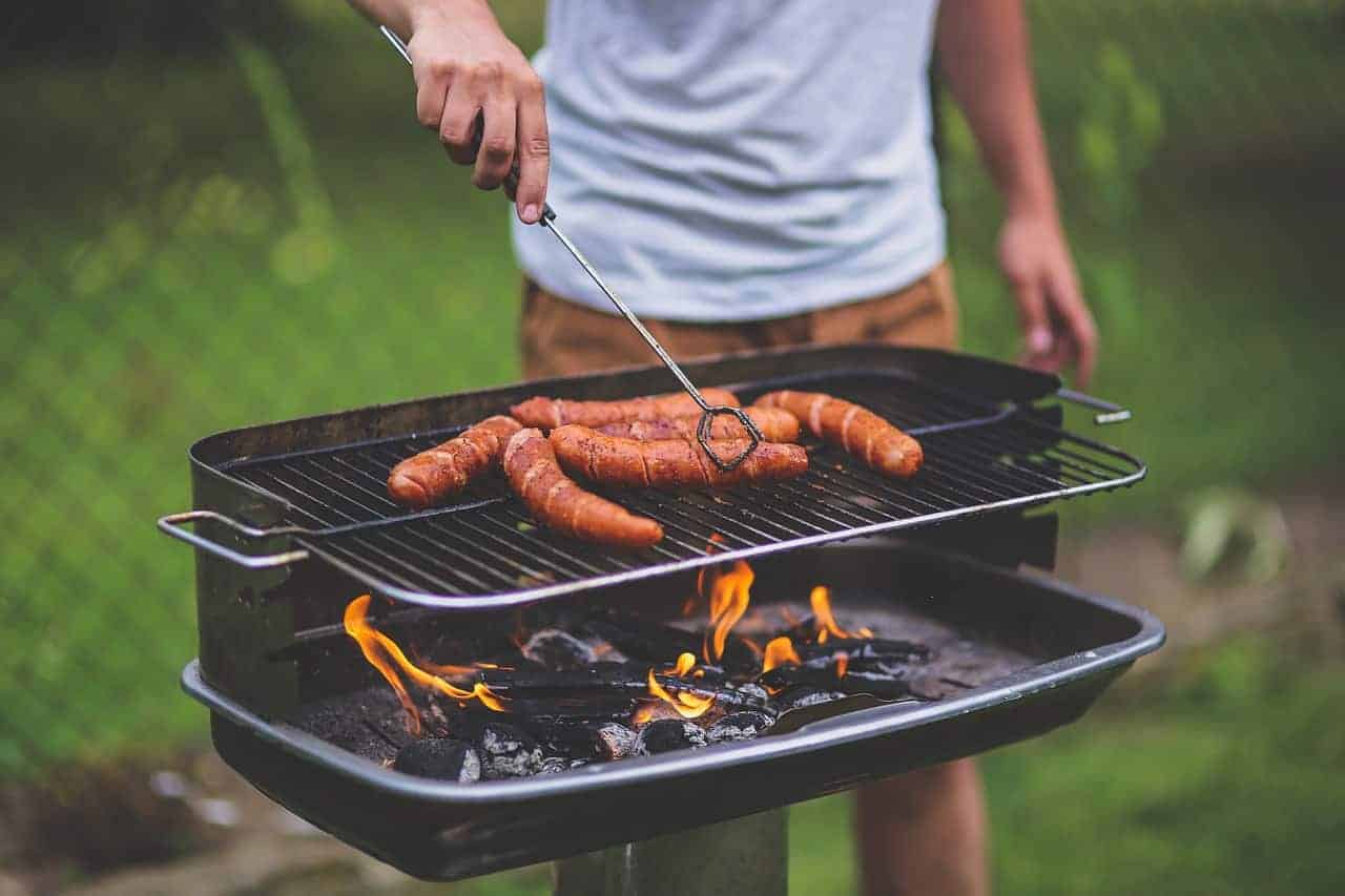 A man grilling polish sausages on a grill.