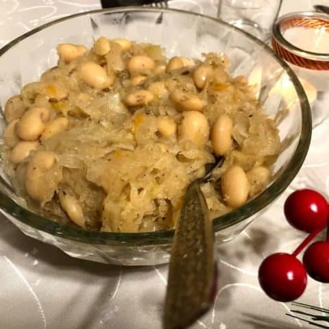 A bowl of white beans and sauerkraut, a classic Polish dish, on a table.