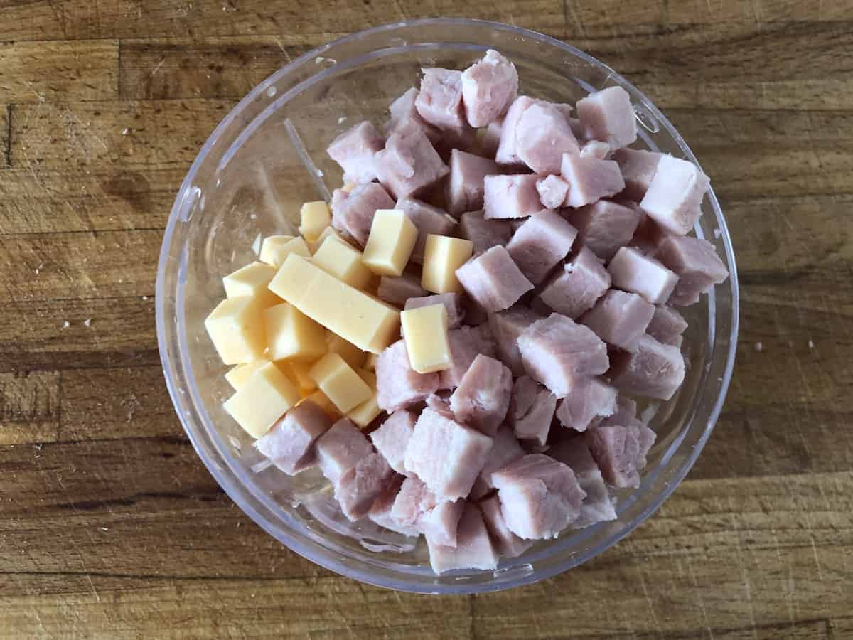 A traditional Polish cold dish made with ham and cheese, featuring stuffed tomatoes, presented on a wooden table.
