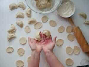 A child's hands roll dough for a vegan pierogi recipe.