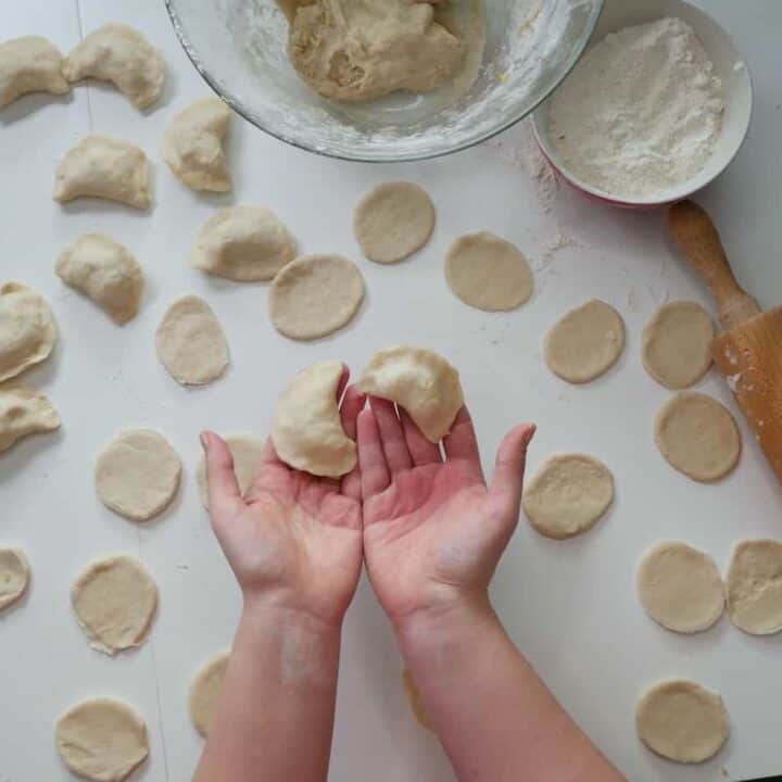 A child's hands roll dough for a vegan pierogi recipe.