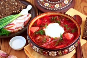 A bowl of Ukrainian Style barszcz ukrainski, a Polish beet soup, served with bread and sour cream.
