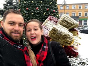 A couple taking a selfie in front of a Christmas tree during the festive season.