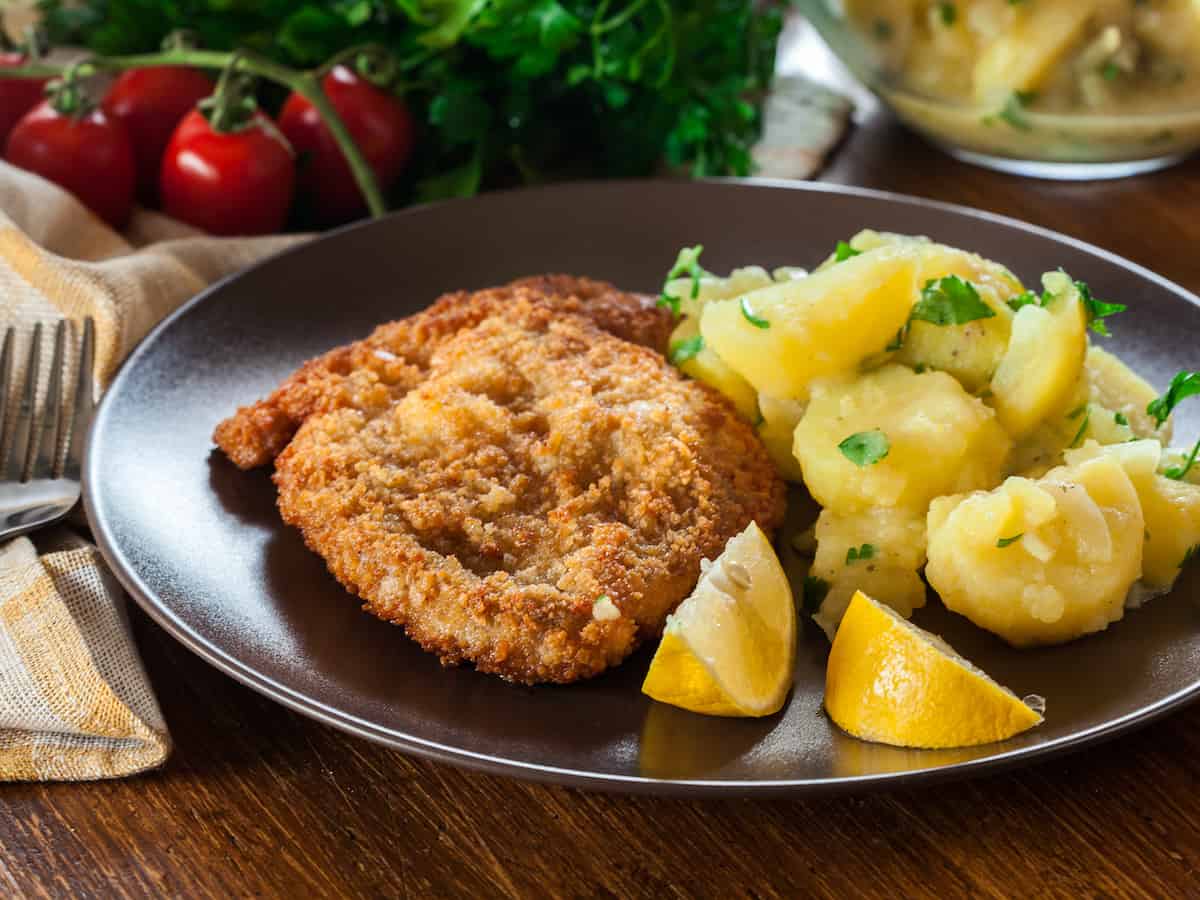 Polish pork cutlets schnitzel with mashed potatoes and lemons on a plate.