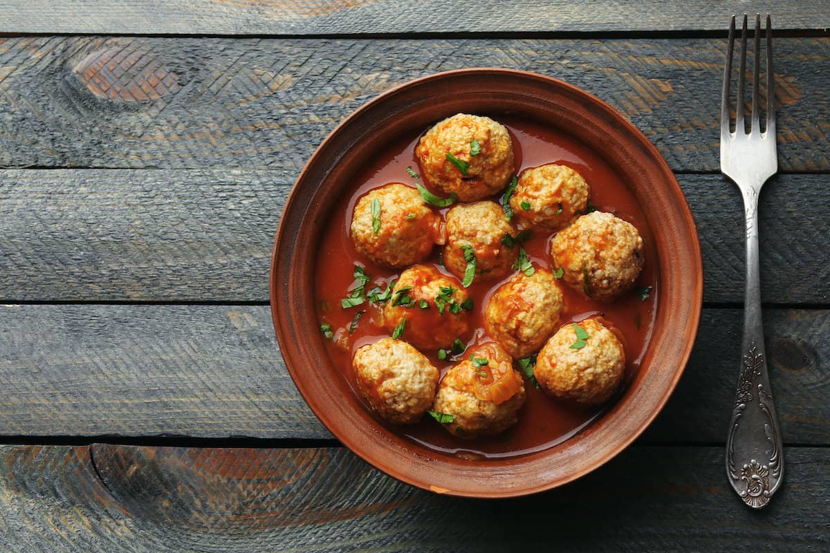 Polish meatballs in tomato sauce on a wooden table.