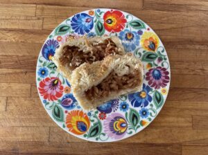 A plate with a piece of apple pie on it, drizzled with apple cinnamon.