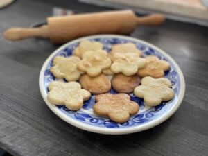 A plate of Polish Butter Cookies on a table next to a rolling pin.