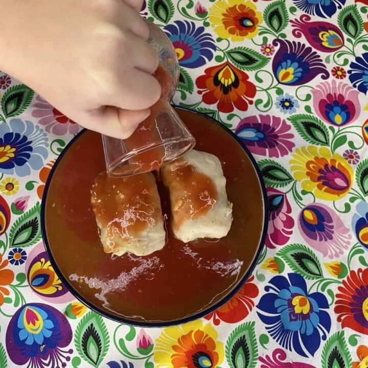 A person pouring authentic sauce on a plate of Polish golumpki.
