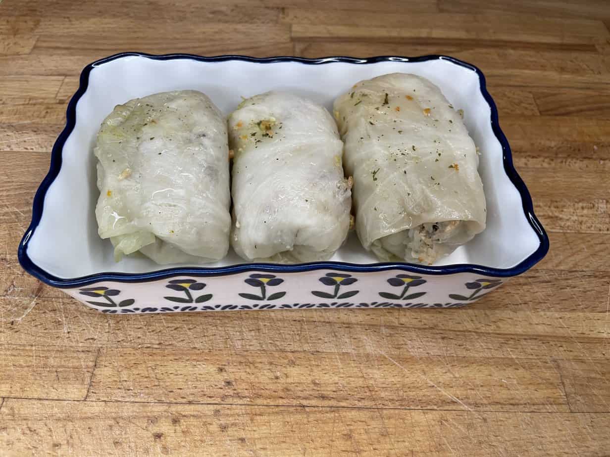 Authentic Polish golumpki recipe featuring three stuffed cabbage rolls in a blue and white dish.