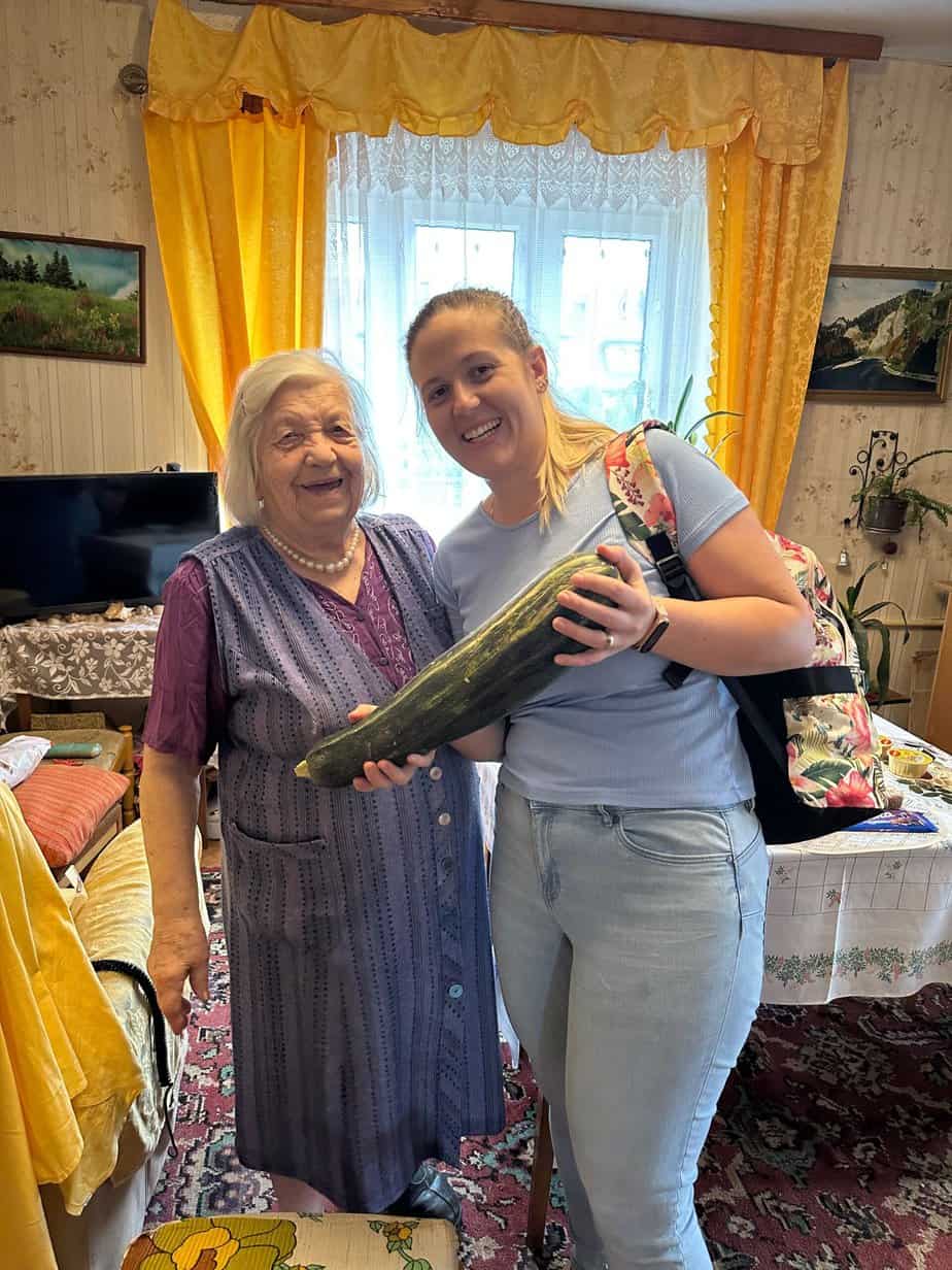 A woman holding a cucumber in her living room.