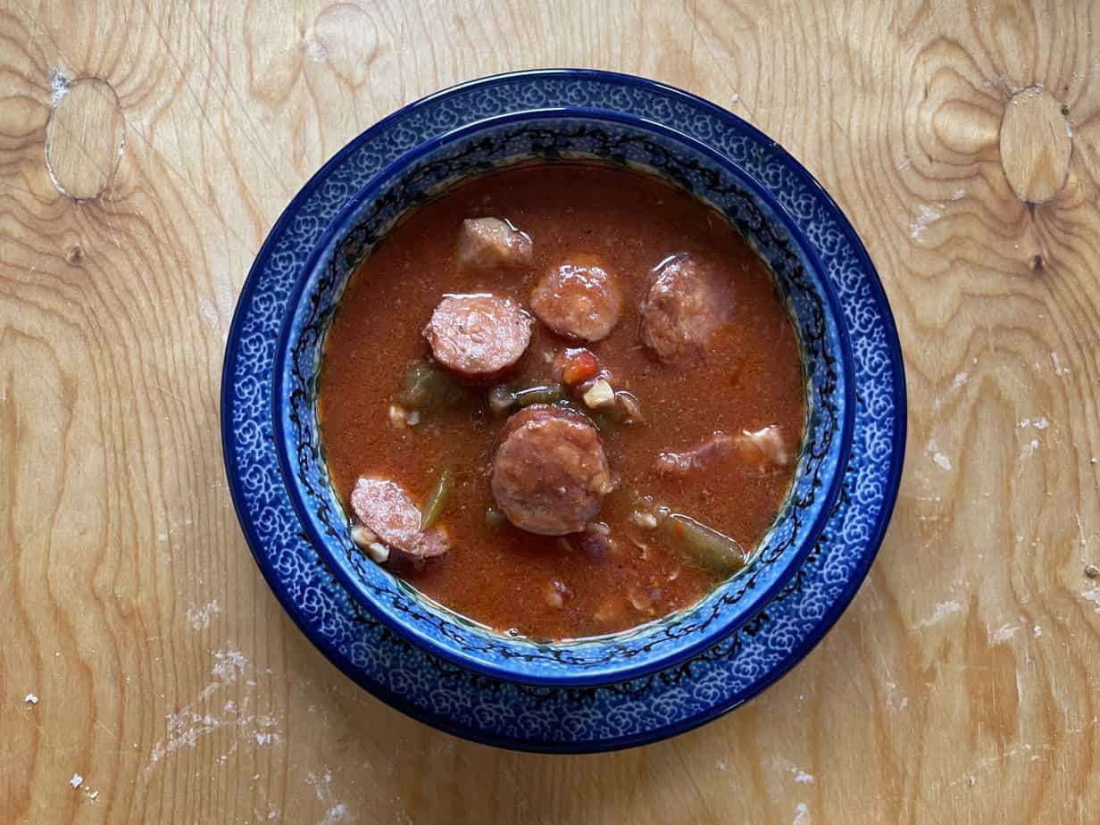 A traditional Polish meat stew recipe featuring sausage and vegetables, served steaming hot on a rustic wooden table.