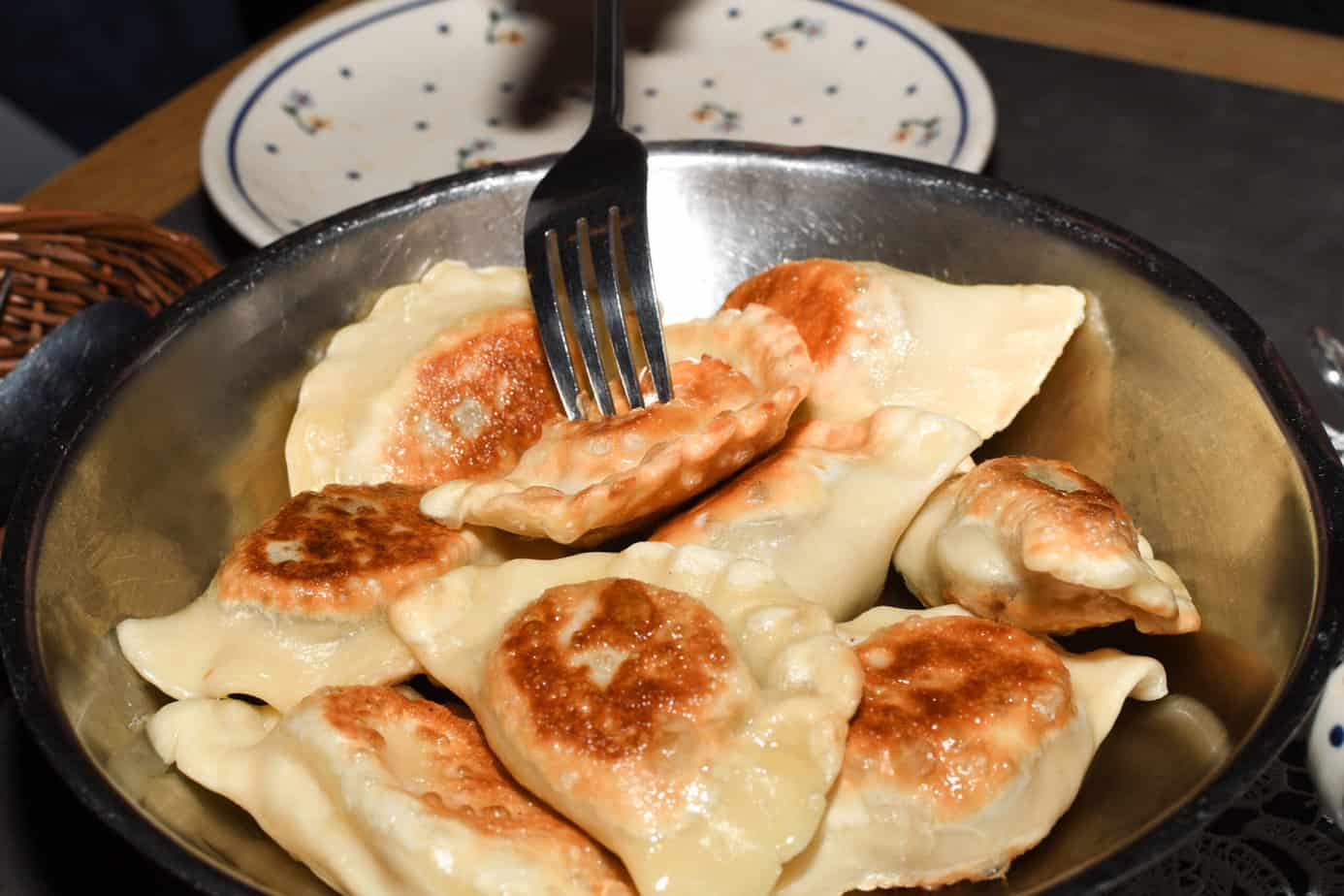 A plate of freshly baked pierogi with a fork.