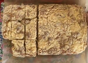 A crumb-topped Polish Yeast Cake, partly sliced, rests invitingly on parchment paper.