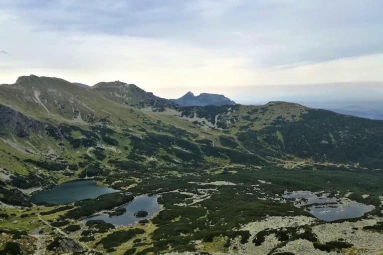 Mountain landscape with rolling green hills, rocky terrain, and several small lakes under a cloudy sky—discover this off the beaten path gem near Zakopane, Poland, perfect for unique adventures and new things to do.